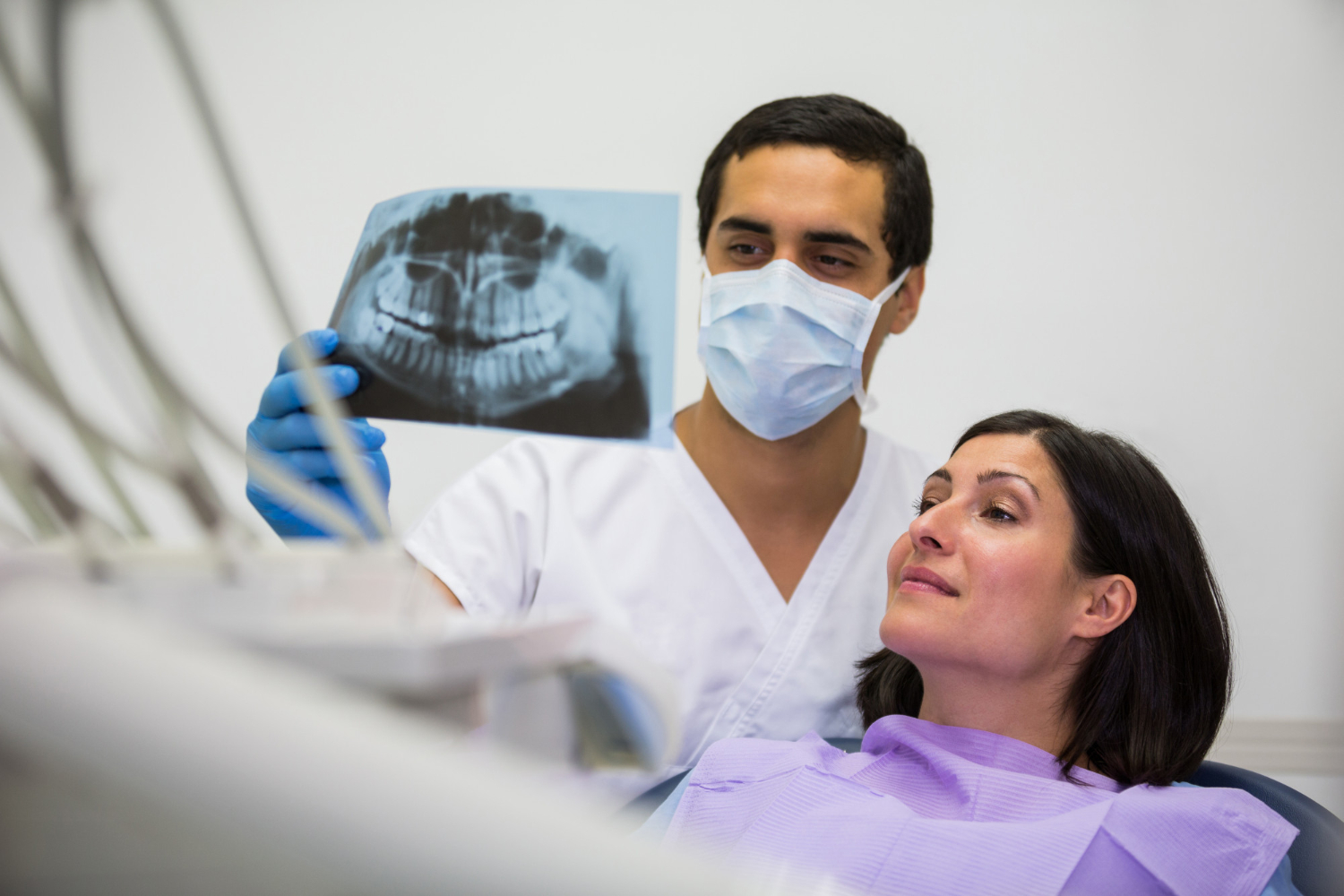 young-male-dentist-examining-x-ray-with-female-patient